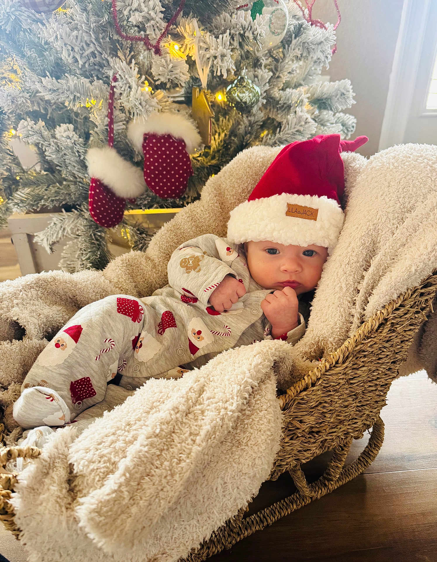 Grayson joined the competition — help win amazing prizes! baby, infant, christmas_tree, santa_hat, blanket, basket, pajamas, holiday, decorations, mittens, indoors, festive, cute, cozy, sleepwear, wooden_floor, soft_lighting, wrapped, seasonal, relaxing