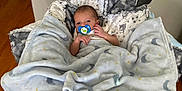 Harrison joined the competition — help win amazing prizes! baby, baby_swing, blanket, child, comfort, cozy, cute, floor, indoor, infant, newborn, pacifier, person, portrait, resting, sleepy, soft, star, toy, wooden_floor
