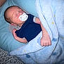 newborn, baby, sleeping, pacifier, blanket, blue_blanket, cushion, onesie, infant, sleep, bed, leopard_print, soft_texture, cozy, hand, face, head, rest, indoor, comfort