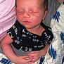 Harrison is registered to the contest to win money with this photo: newborn, baby, sleeping, blanket, quilt, black_clothing, infant, human_hand, skin, face, person, rest, peaceful, young_child, textile, pattern, closeup, indoor, comfort, toddler