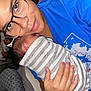 baby, person, glasses, blue_shirt, striped_blanket, newborn, hand, indoor, bedroom, blanket, sleeping, closeup, face, caring, comfort, resting, mother_and_baby, skin, human, portrait