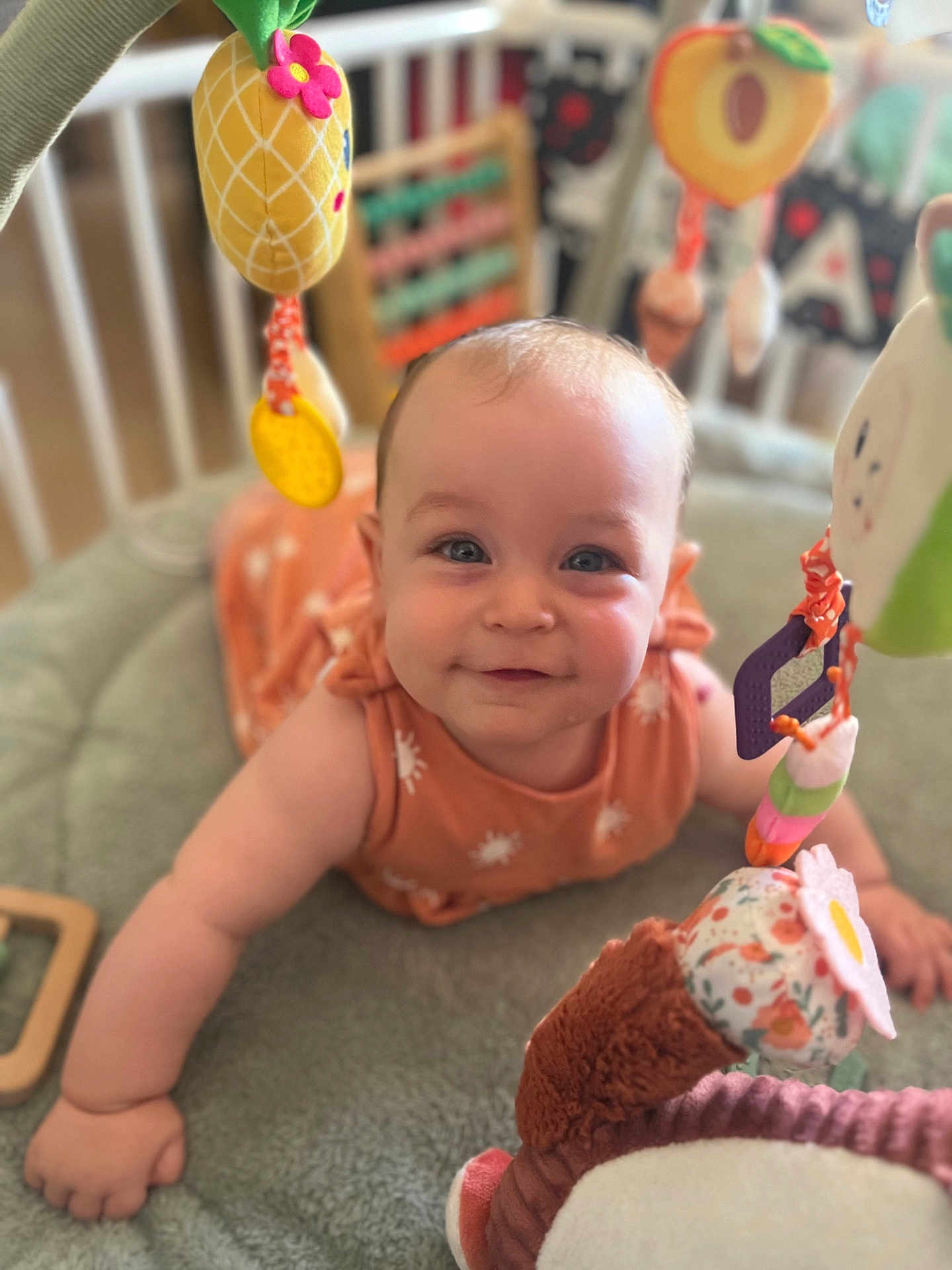 Charlotte a rejoint le concours — aidez-le/la à gagner de superbes lots ! baby, infant, smiling, face, eyes, arm, hand, blanket, toy, pineapple, flower, soft_toy, colorful, cute, indoors, crawling, child, playtime, crib, happy