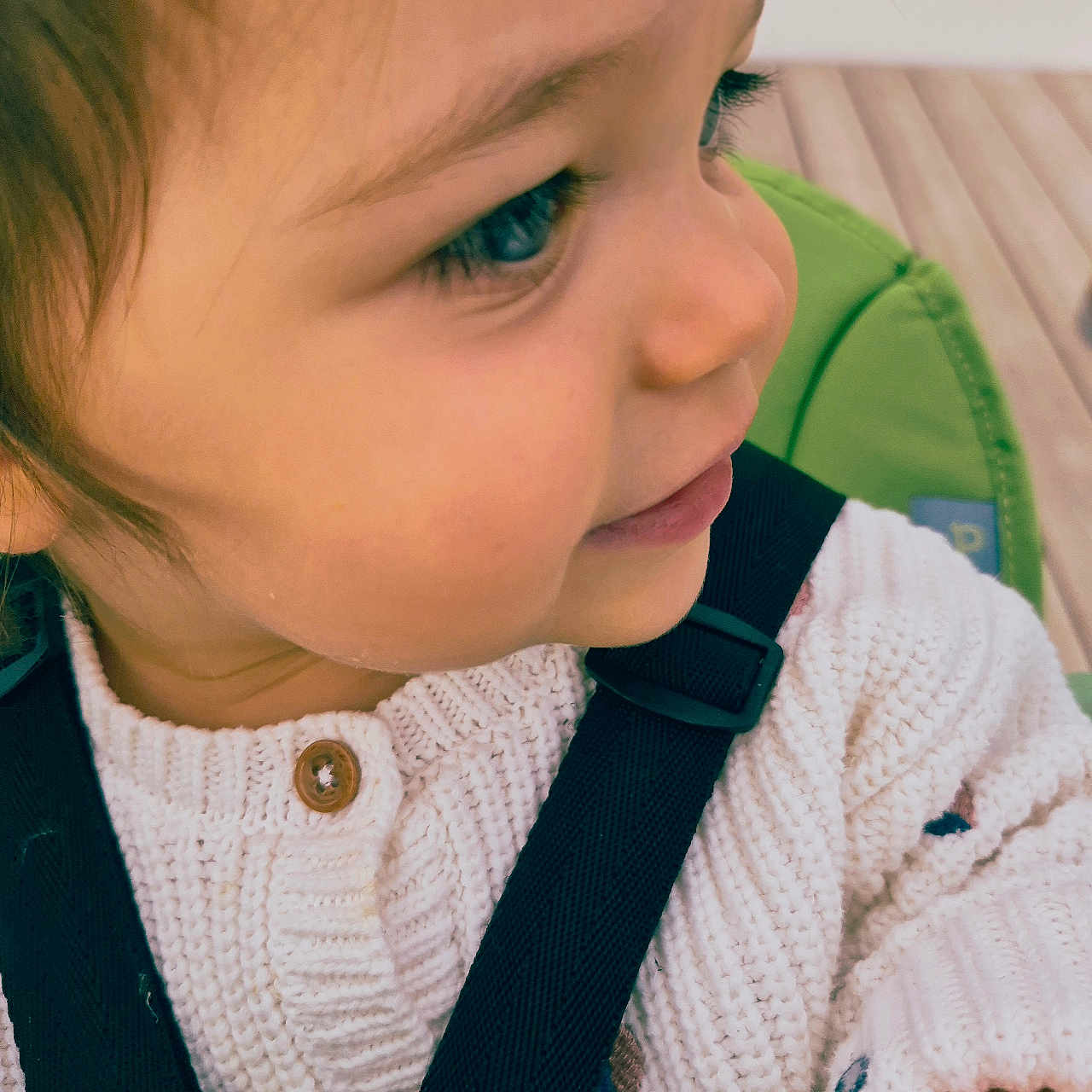 Garance participe au concours pour gagner de l'argent avec cette photo : baby, button, child, clothing, curly_hair, cute, face, green, indoors, knitted_sweater, long_eyelashes, person, portrait, profile, seat, skin, smile, straps, toddler, young_child