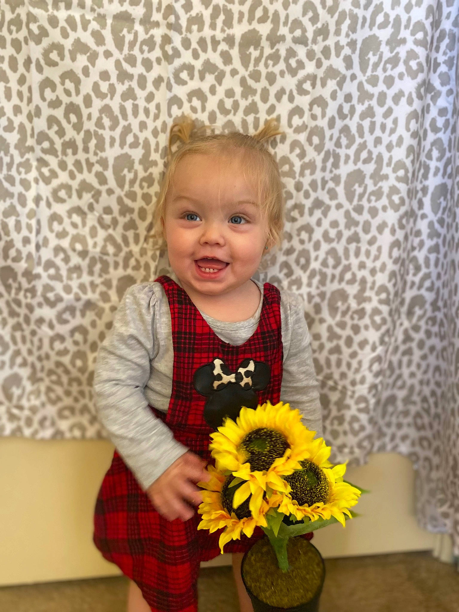 Dixie Jo is registered to the contest to win money with this photo: baby_toddler_clothing, child, dress, eye, flower, flower_arranging, flowerpot, hair, hand, happy, iris, person, petal, plant, sleeve, smile, standing, tartan, textile, toddler