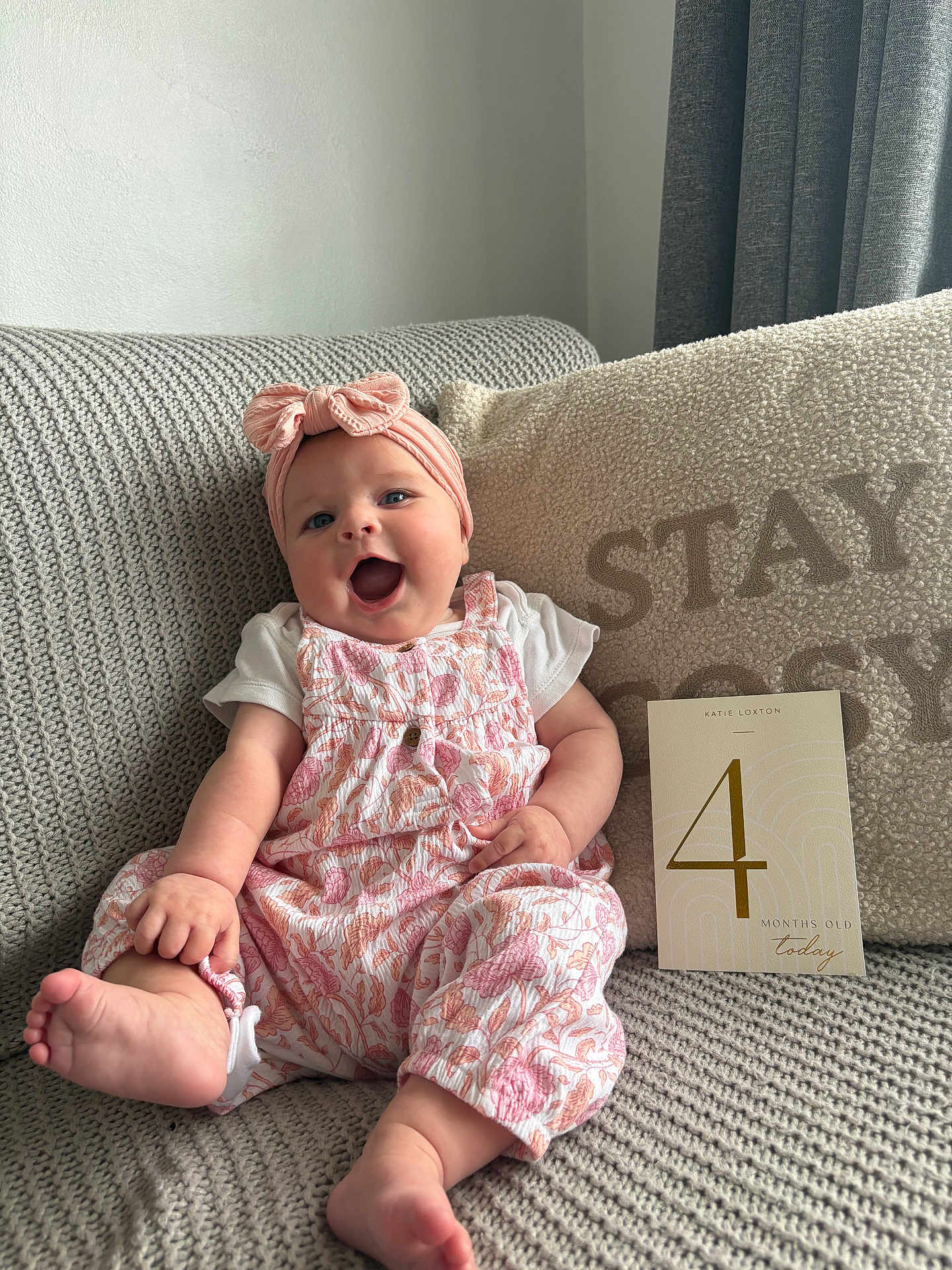 Ava joined the competition — help win amazing prizes! baby, infant, smiling, sitting, couch, knitted, headband, pink, white, floral, milestone_card, cozy, pillow, happy, cute, indoors, child, portrait, soft_lighting, home