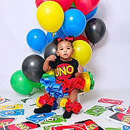 Chozyn joined the competition — help win amazing prizes! toddler, child, balloons, uno_cards, colorful, party, costume, black_socks, red_bows, studio, playful, celebration, game, cute, portrait, smiling, sitting, indoors, bright, fun