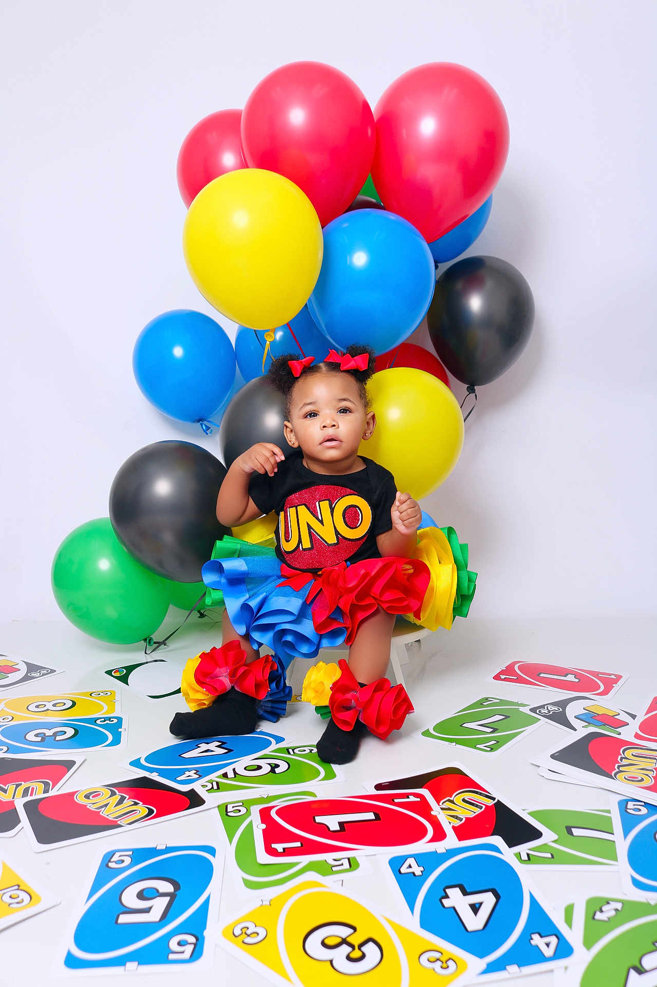Chozyn joined the competition — help win amazing prizes! toddler, child, balloons, uno_cards, colorful, party, costume, black_socks, red_bows, studio, playful, celebration, game, cute, portrait, smiling, sitting, indoors, bright, fun
