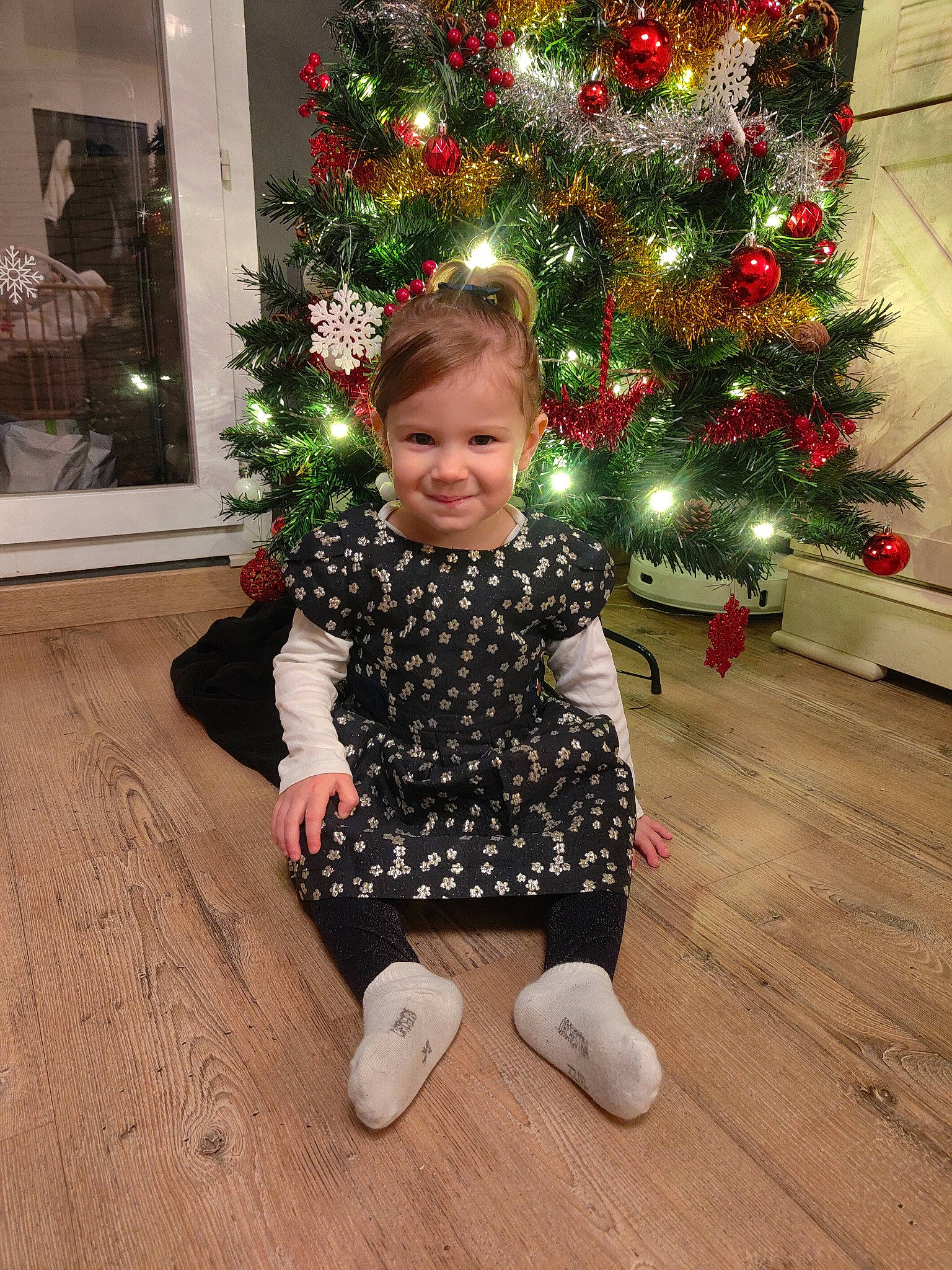 Elena participe au concours pour gagner de l'argent avec cette photo : baby_toddler_clothing, christmas, christmas_decoration, christmas_eve, christmas_ornament, christmas_tree, event, flooring, happy, hardwood, holiday, holiday_ornament, joy, person, plant, sleeve, smile, sock, standing, toddler