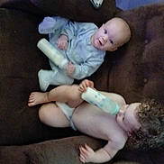 Damon joined the competition — help win amazing prizes! baby, toddler, bottle, couch, brown_furniture, child, indoors, curly_hair, clothing, diaper, feeding, sitting, face, person, carpet, plush, relaxing, cute, infant, home