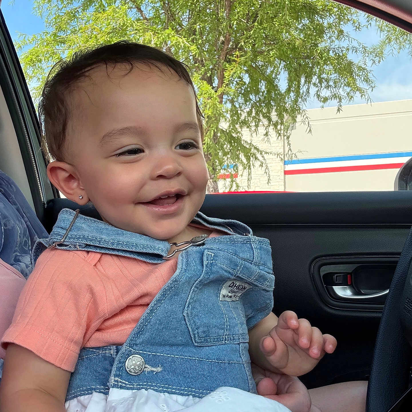 Julianna joined the competition — help win amazing prizes! car, casual, child, clothing, daylight, denim, earring, face, happy, joy, outdoor, overalls, person, portrait, seat, smiling, toddler, tree, vehicle, window