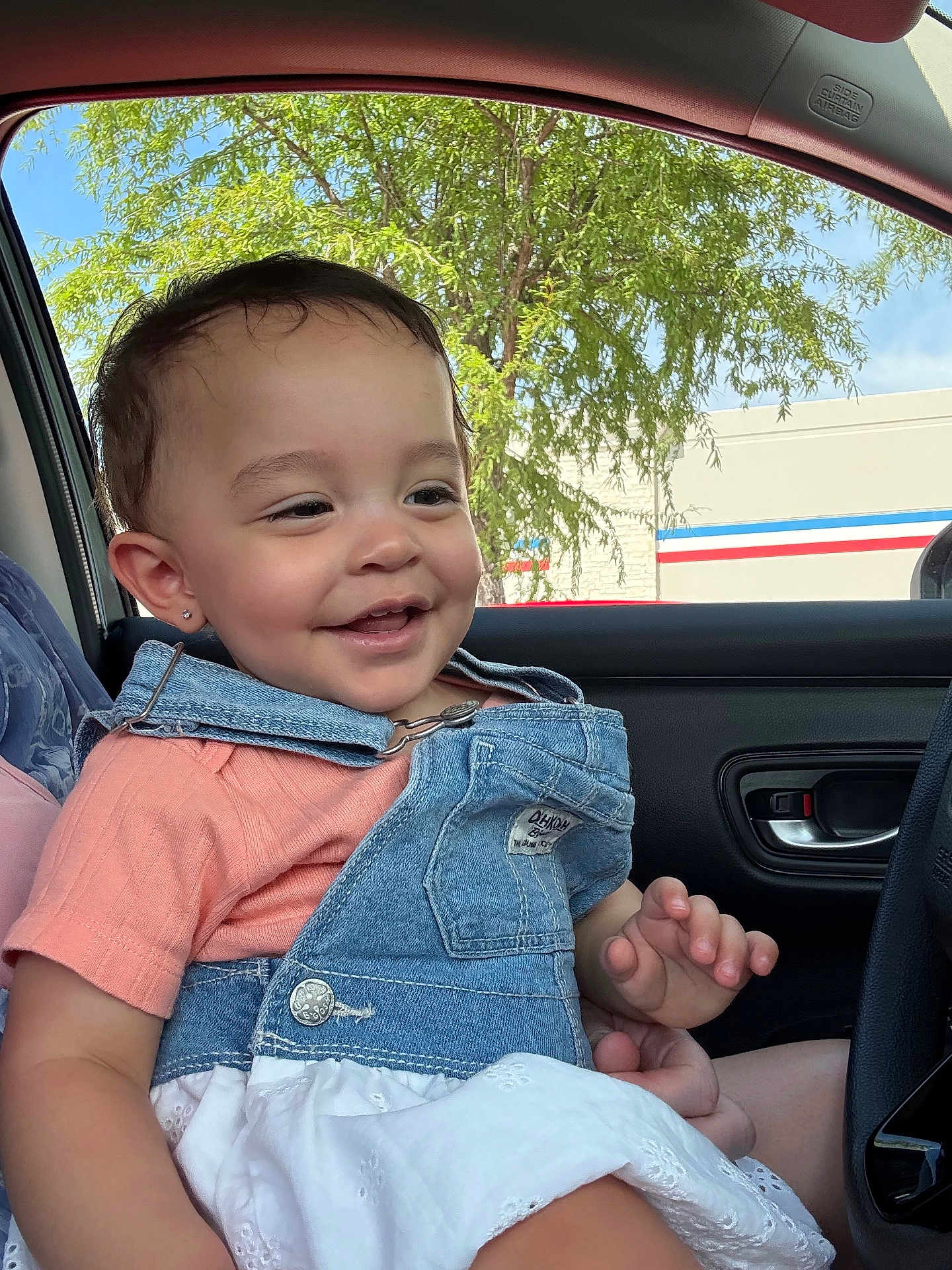 Julianna joined the competition — help win amazing prizes! toddler, child, smiling, denim, overalls, earring, car, window, tree, outdoor, clothing, happy, face, person, seat, portrait, casual, daylight, vehicle, joy