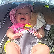 Winter is registered to the contest to win money with this photo: baby, smiling, pink_hat, pink_shirt, stroller, blanket, plush_toy, outdoor, child, happy, legs, feet, sunshade, cute, infant, playful, summer, seat, clothing, person