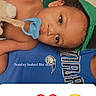 baby, blue_shirt, casual, child, clothing, cute, emoji, face, green_cap, hand_gesture, heart_emoji, indoor, infant, lying_down, pacifier, person, relaxed, skin, smiling_face_emoji, text_overlay