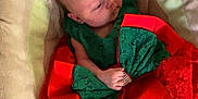 Izabella-Mae joined the competition — help win amazing prizes! baby, infant, child, dress, red_bow, lace, green_clothing, cushion, seat, soft_fabric, indoor, portrait, cute, small_hands, head, face, looking_sideways, comfortable, resting, newborn