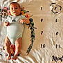 éden a rejoint le concours — aidez-le/la à gagner de superbes lots ! baby, infant, onesie, blanket, floral, numbers, months, lying_down, curious, skin, feet, hands, face, head, soft_texture, colorful, pattern, cute, child, portrait