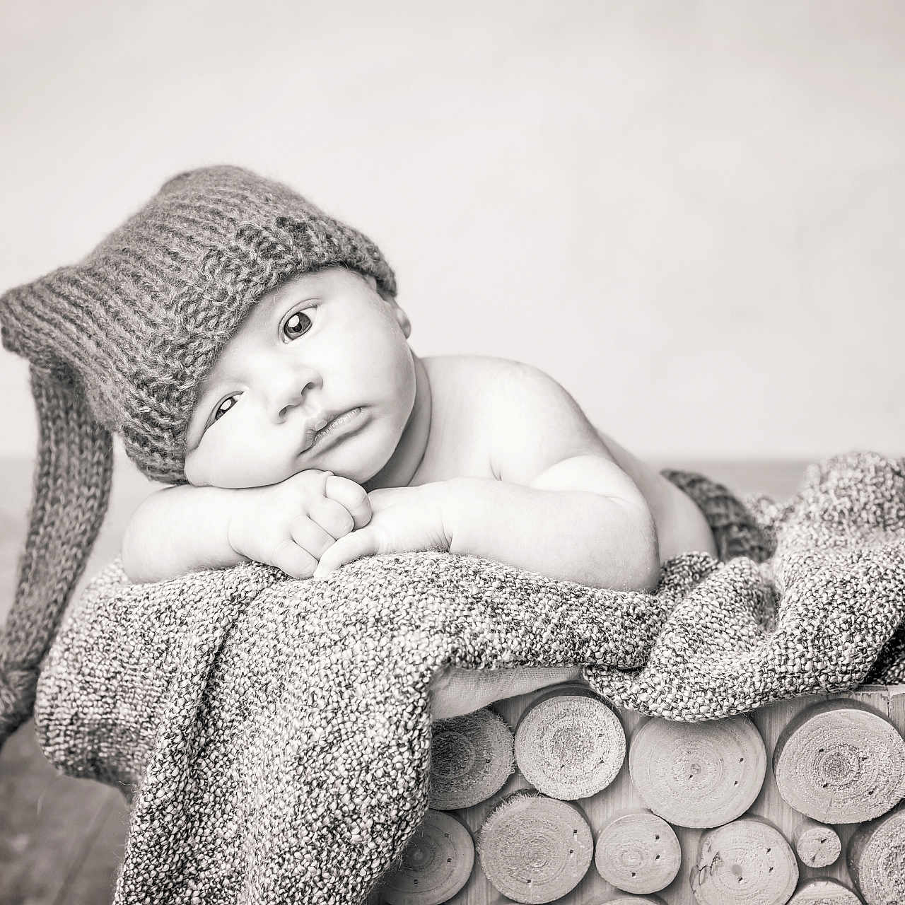 éden a rejoint le concours — aidez-le/la à gagner de superbes lots ! baby, black_and_white, blanket, child, closeup, cozy, cute, floor, hat, indoors, infant, knitted_hat, log_basket, peaceful, portrait, relaxed, resting, sleepy, soft_texture, wood
