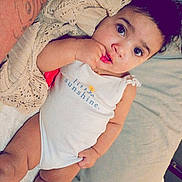 Bryliee joined the competition — help win amazing prizes! baby, bed, blanket, child, cozy, curly_hair, cute, expression, eyes, face, hand, infant, intimate, lying_down, nibbling, onesie, person, skin, soft, tattoo