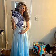 Symone is registered to the contest to win money with this photo: girl, child, dress, fan, barefoot, headband, indoor, door, shopping_bag, floor, wooden_floor, shoes, sneakers, slippers, smile, person, standing, wall, light_switch, casual