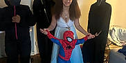 Symone joined the competition — help win amazing prizes! child, costume, halloween, indoor, spiderman, dress, hood, mask, person, floor, living_room, light, smile, group, wood_floor, furniture, curtain, headwear, pose, people