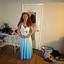 Symone is registered to the contest to win money with this photo: girl, dress, standing, indoor, mirror, door, floor, table, bag, shoes, wooden_floor, long_hair, smile, casual, room, reflection, jewelry, headband, furniture, clothing