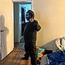 child, costume, black_clothing, mask, pose, living_room, doorway, wood_floor, shadow, sock, bag, blanket, couch, curtains, indoor, person, home, flooring, fist, standing