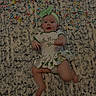 Lilly is registered to the contest to win money with this photo: baby, child, infant, st_patricks_day, green_bow, dress, candy, rug, patterned_rug, celebration, holiday, smiling, happy, lying_down, cute, festive, clothing, indoors, person, headband