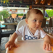 Elias Mikhaël a rejoint le concours — aidez-le/la à gagner de superbes lots ! baby, child, high_chair, restaurant, table, indoor, people, furniture, glass, plant, outdoor, dining, blur, hand, shirt, text, face, seat, wood, casual