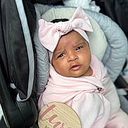 Makayla joined the competition — help win amazing prizes! baby, infant, car_seat, pink_clothing, headband, bow, milestone_sign, pacifier, wrapped, portrait, indoor, cute, child, face, expression, soft_texture, blanket, newborn, sitting, person