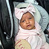 baby, infant, car_seat, pink_clothing, headband, bow, milestone_sign, pacifier, wrapped, portrait, indoor, cute, child, face, expression, soft_texture, blanket, newborn, sitting, person