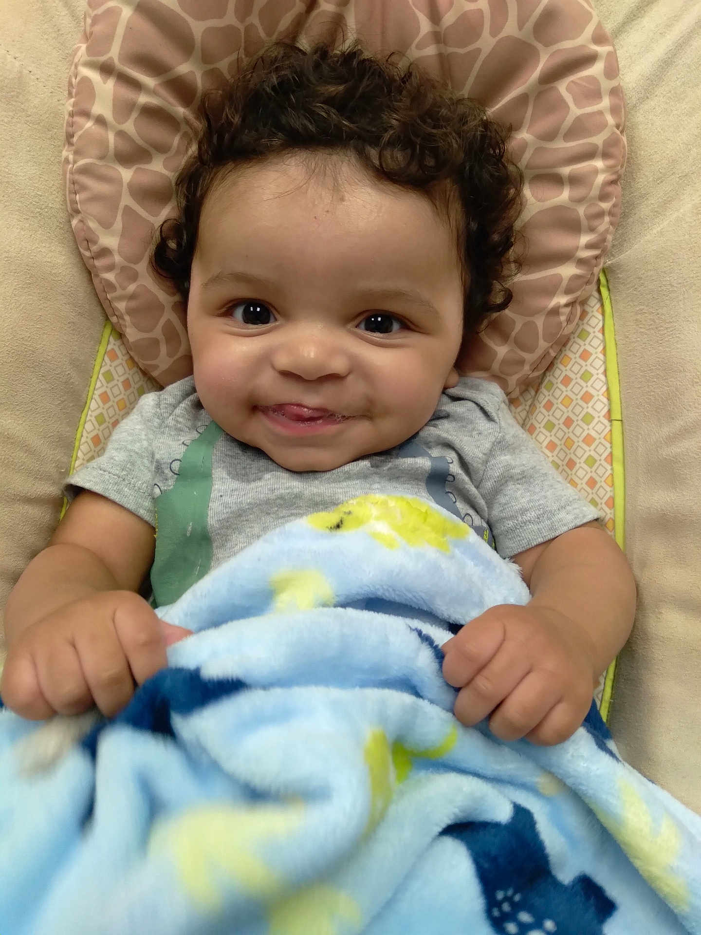 Hyland is registered to the contest to win money with this photo: baby, smiling, curly_hair, blanket, blue_blanket, baby_seat, infant, cute, child, portrait, happy, face, hands, cozy, toddler, indoor, soft_texture, patterned_blanket, closeup, playful
