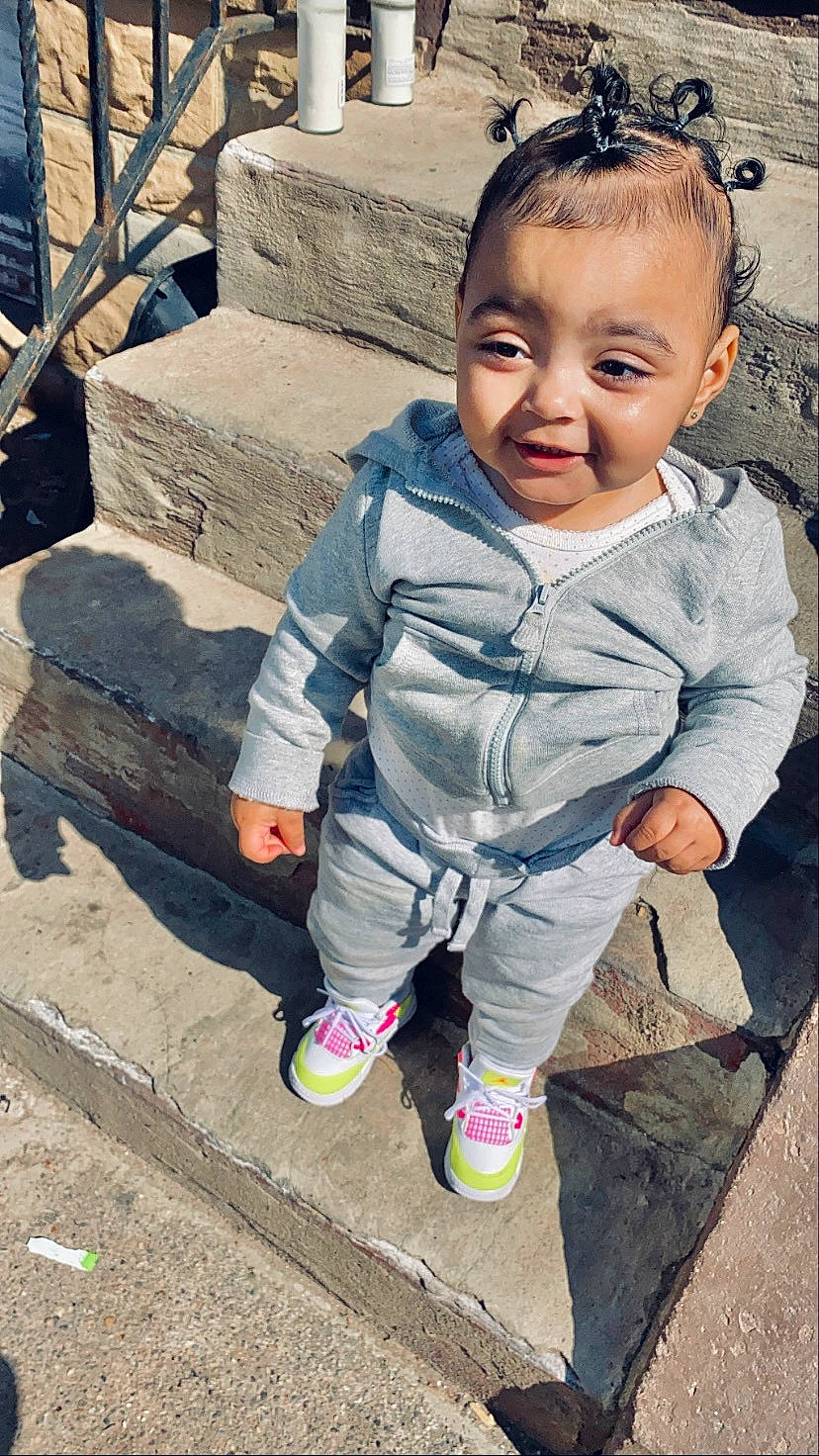 Sariah is registered to the contest to win money with this photo: baby, baby_toddler_clothing, cheek, child, cool, eye, facial_expression, foot, forehead, fun, grass, hairstyle, happy, head, leisure, people, person, sitting, skin, sneakers