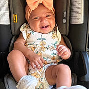 Melanie joined the competition — help win amazing prizes! accessory, baby, bow, car_seat, child, clothing, cute, floral_clothing, happy, headband, indoors, infant, person, portrait, seat_belt, sitting, smiling, toddler, white_socks, young_child