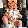accessory, baby, bow, car_seat, child, clothing, cute, floral_clothing, happy, headband, indoors, infant, person, portrait, seat_belt, sitting, smiling, toddler, white_socks, young_child