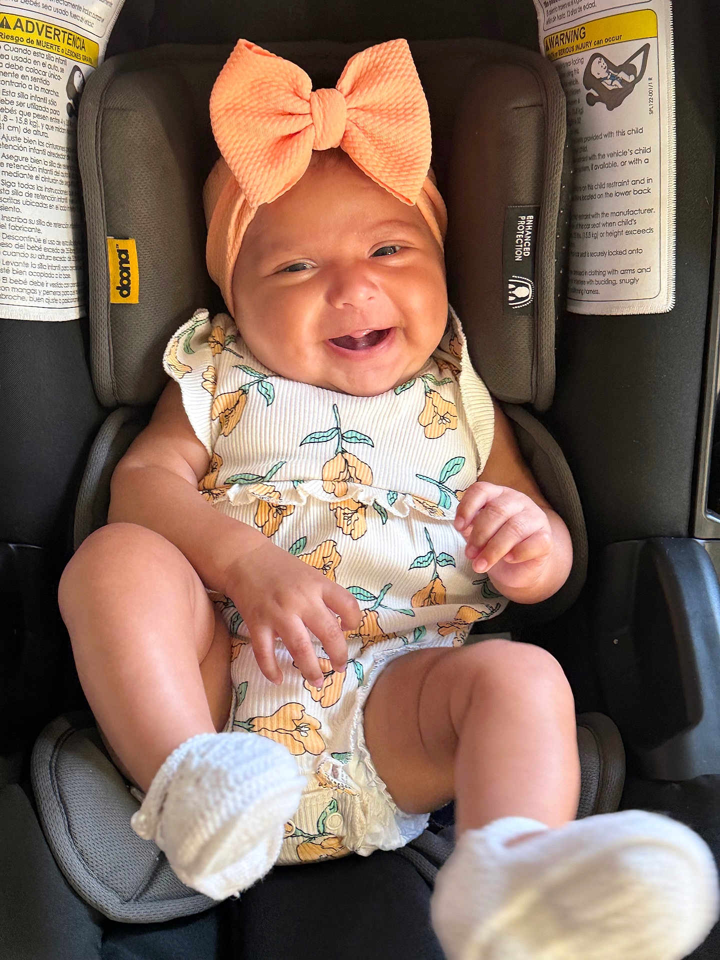 Melanie joined the competition — help win amazing prizes! accessory, baby, bow, car_seat, child, clothing, cute, floral_clothing, happy, headband, indoors, infant, person, portrait, seat_belt, sitting, smiling, toddler, white_socks, young_child