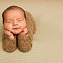 baby, newborn, infant, sleeping, closed_eyes, hands, chin, brown_knit_outfit, cozy, soft_texture, beige_background, portrait, cute, peaceful, resting, child, tiny_hands, warm, indoors, studio_photo