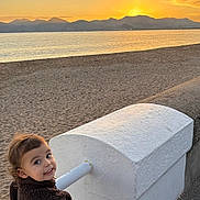 Carmela participe au concours pour gagner de l'argent avec cette photo : toddler, child, smile, jacket, scooter, pink, beach, sunset, mountains, water, sand, outdoor, person, happy, scenic, sunlight, nature, sky, play, leisure