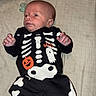 baby, infant, child, skeleton_costume, halloween, ghost, onesie, black_clothing, white_bones, pacifier, bed, blanket, lying_down, portrait, face, hands, feet, indoors, cozy, surprised
