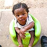 Zyaire joined the competition — help win amazing prizes! baby, child, infant, green_baby_seat, concrete_floor, curly_hair, white_onesie, star_pattern, barefoot, hands, feet, outdoor, sunlight, sandals, person, cute, young_child, seated, looking_up, expression