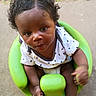 Zyaire is registered to the contest to win money with this photo: baby, child, curly_hair, green_baby_seat, drool, white_shirt, stars_pattern, outdoor, concrete_floor, barefoot, infant, looking_up, cute, small_hands, sitting, casual_clothing, young_child, black_hair, expression, bright_colors