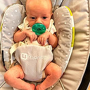 Neveah is registered to the contest to win money with this photo: baby, infant, pacifier, baby_seat, cushion, gray, polka_dot, hands, legs, feet, clothing, newborn, comfort, child, cute, indoors, relax, person, baby_bouncer, skin