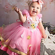 Maddie joined the competition — help win amazing prizes! baby, child, pink_dress, bow_headband, smiling, happy, flower_background, cute, tulle_skirt, barefoot, indoor, portrait, decorative_chair, headband, toddler, joyful, posed, colorful, feminine, celebration