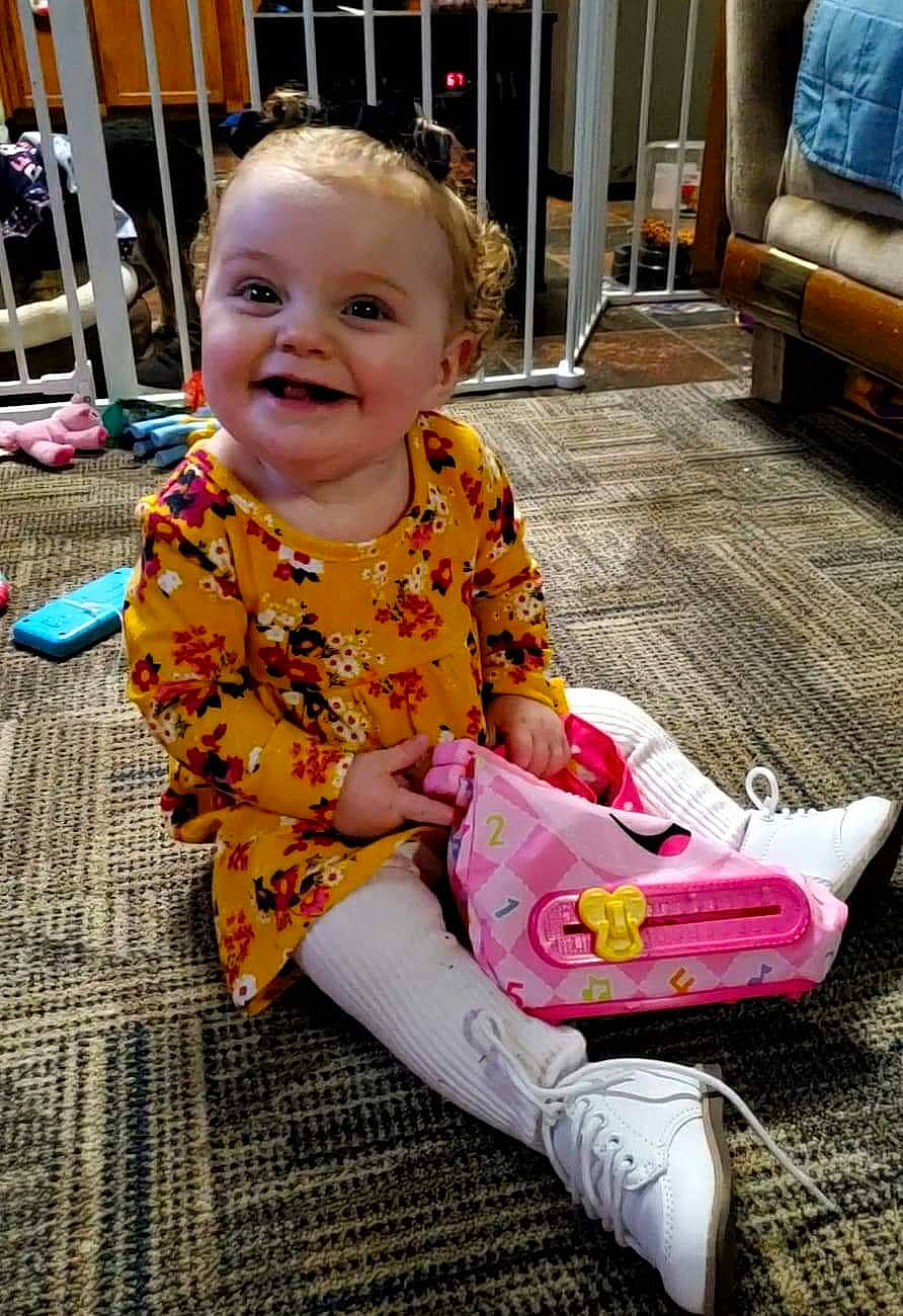 Adalie is registered to the contest to win money with this photo: baby, baby_toddler_clothing, cheek, child, comfort, eye, face, flooring, fun, hair, happy, head, iris, joy, lap, leisure, person, pink, sitting, skin