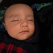 Elijah is registered to the contest to win money with this photo: baby, sleeping, infant, face, portrait, blanket, bundled, swaddled, indoors, cozy, peaceful, closed_eyes, dark_clothing, red_plaid, textile, resting, head, child, closeup, photography