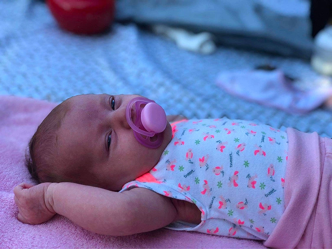 Maëlle participe au concours pour gagner de l'argent avec cette photo : baby, baby_toddler_clothing, cheek, comfort, eye, face, finger, hand, head, human_body, linens, lip, mouth, nose, person, pink, purple, red, skin, toddler