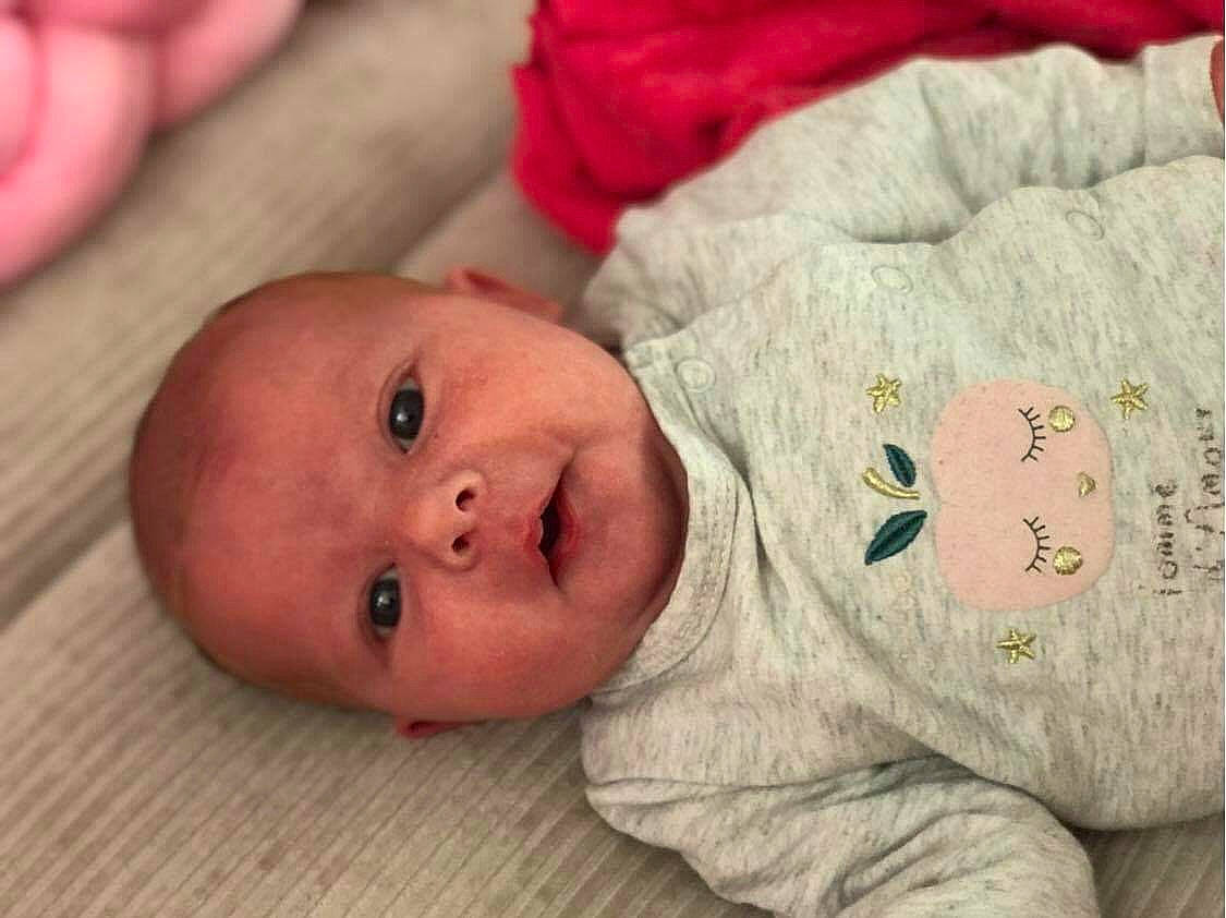 Maëlle a rejoint le concours — aidez-le/la à gagner de superbes lots ! baby, baby_products, baby_toddler_clothing, cheek, child, comfort, eye, face, flooring, head, linens, lip, mammal, nose, person, room, skin, sleeve, smile, toddler