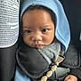 baby, child, face, hood, car_seat, seatbelt, clothing, pacifier_clip, hand, infant, straps, closeup, indoors, expression, cute, young_child, skin, eyes, headwear, safety