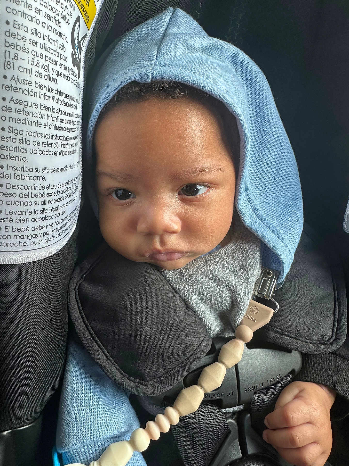 Jaidyn -Andre joined the competition — help win amazing prizes! baby, child, face, hood, car_seat, seatbelt, clothing, pacifier_clip, hand, infant, straps, closeup, indoors, expression, cute, young_child, skin, eyes, headwear, safety