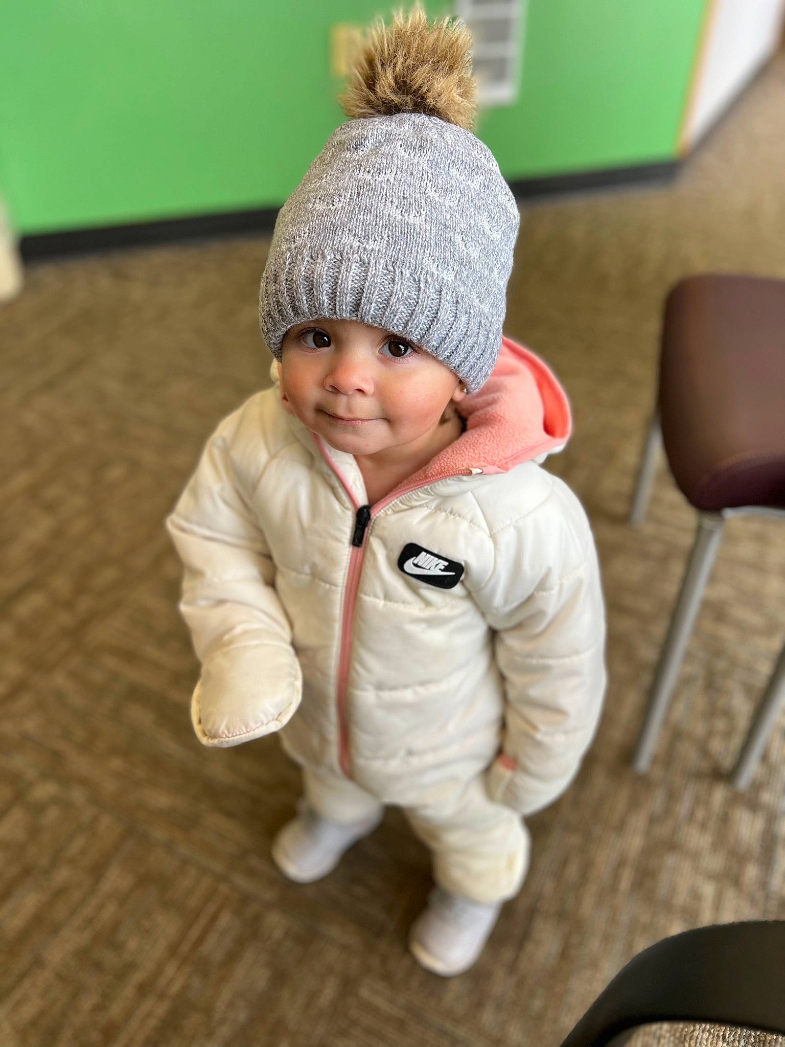 Leila joined the competition — help win amazing prizes! baby, baby_toddler_clothing, beanie, cap, chair, comfort, face, flooring, fur, grass, happy, headgear, headwear, human_body, knit_cap, person, sleeve, smile, toddler, wood