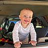 toddler, child, smiling, vehicle, car, window, hands, white_shirt, interior, seat, blanket, happy, cute, portrait, baby, tongue, grip, daylight, casual, candid