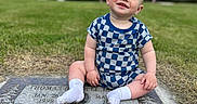 Theodore joined the competition — help win amazing prizes! baby, child, smiling, grass, gravestone, cemetery, outdoor, mountain, sky, clouds, blue_clothing, checkered_pattern, socks, person, nature, portrait, happy, sitting, greenery, daytime